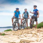 Älteres Pärchen auf Radtour am Meer mit junger Bikeguide