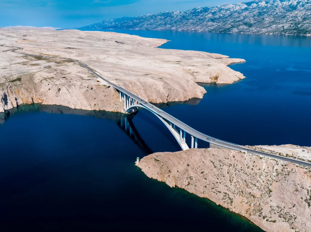 Ponte verso l'isola di Pag e il mare Adriatico e la catena montuosa del Velebit, Jadransko more, Croazia, ripresa aerea con drone