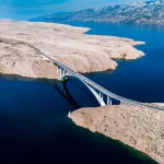 Ponte verso l'isola di Pag e il mare Adriatico e la catena montuosa del Velebit, Jadransko more, Croazia, ripresa aerea con drone