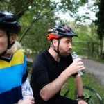 Cyclists resting and drinking water in the forest