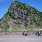 Radfahrer auf Radweg am Rhein entlang an der Loreley bei sonnigem Wetter - Stockfoto