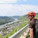 Man with bright orange bike helmet looking out over a panoramic view of the Moselle river